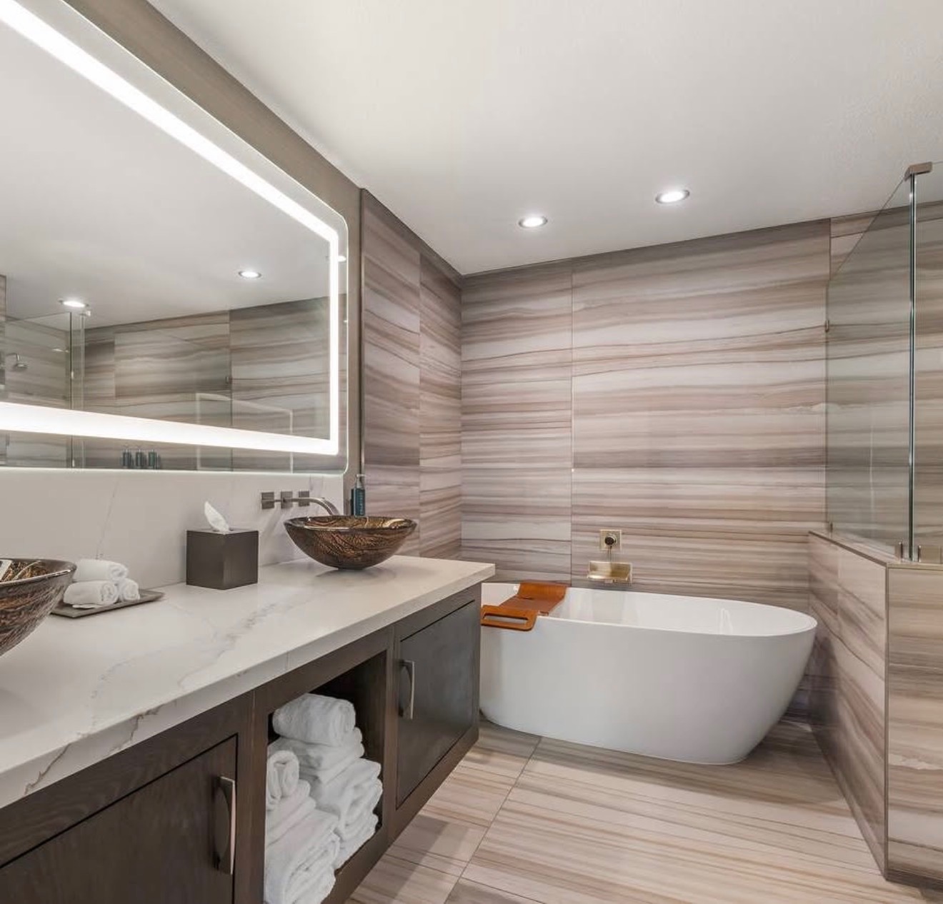 Luxury bathroom with freestanding tub, vessel sinks and backlit mirror