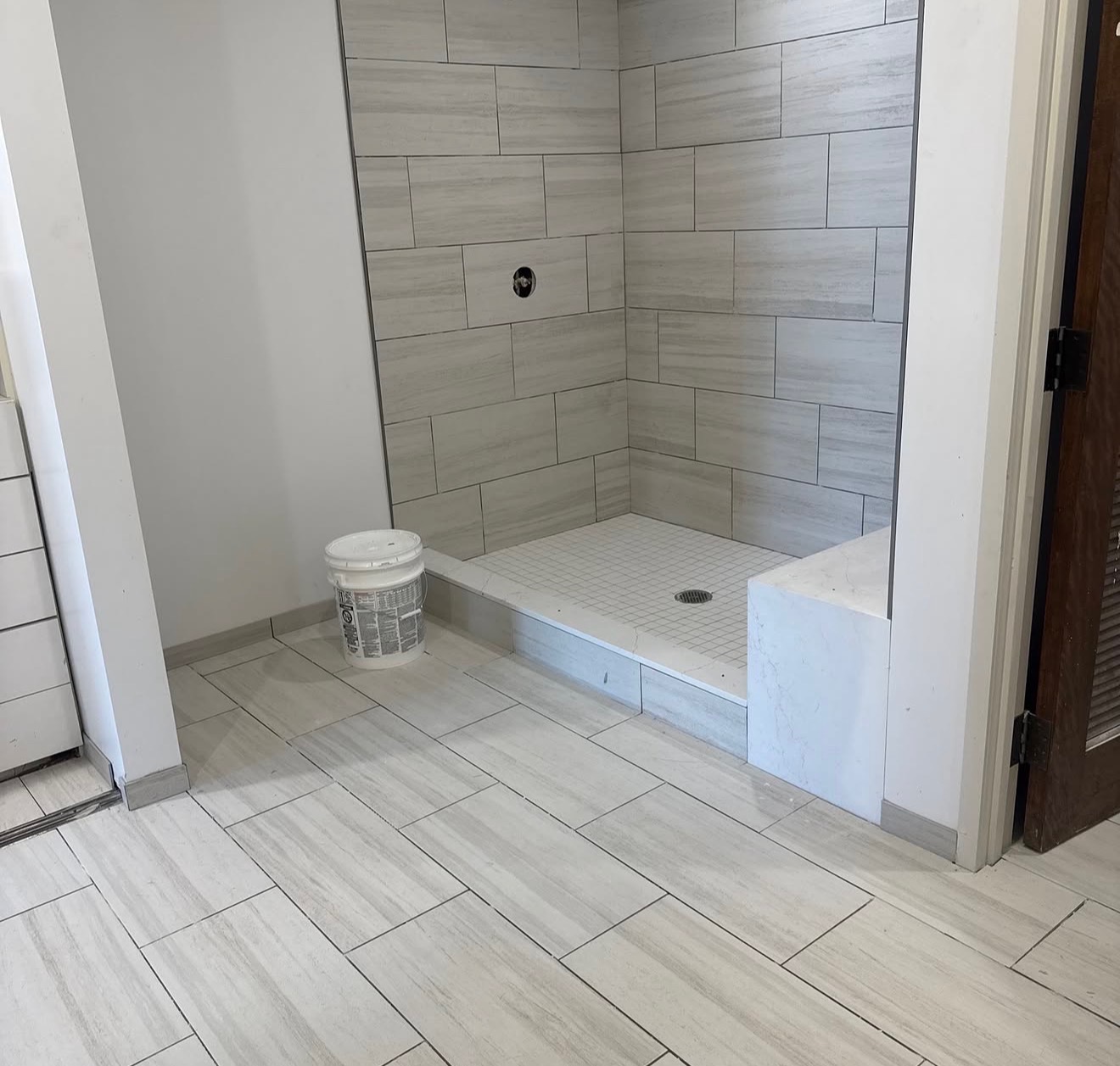 Shower construction with light gray tile and bench